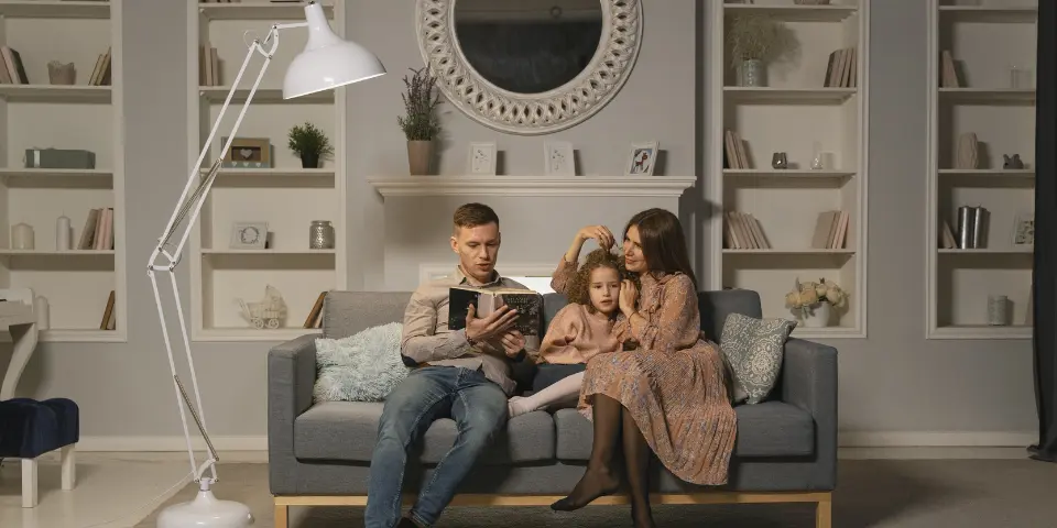 rodzina siedząca na kanapie, czytająca bajkę córce